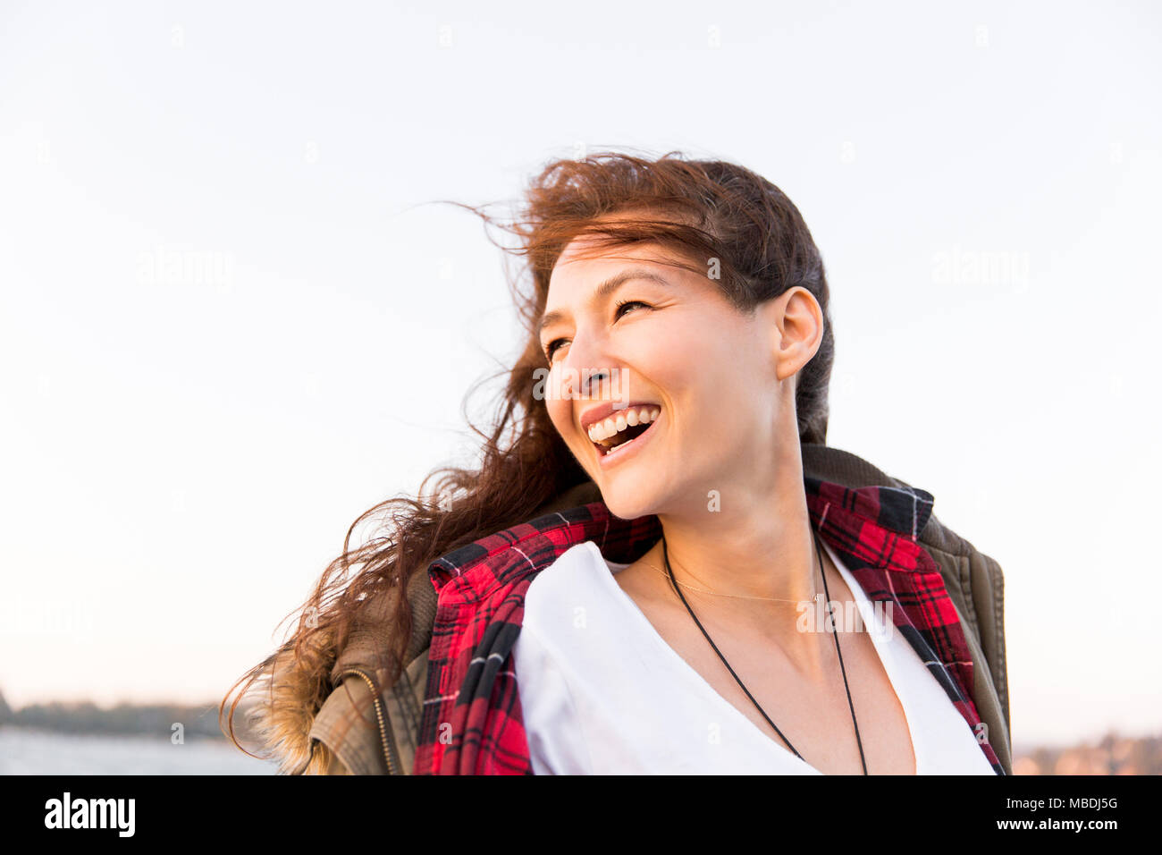 Sorridendo, entusiasta donna guardando sopra la spalla Foto Stock