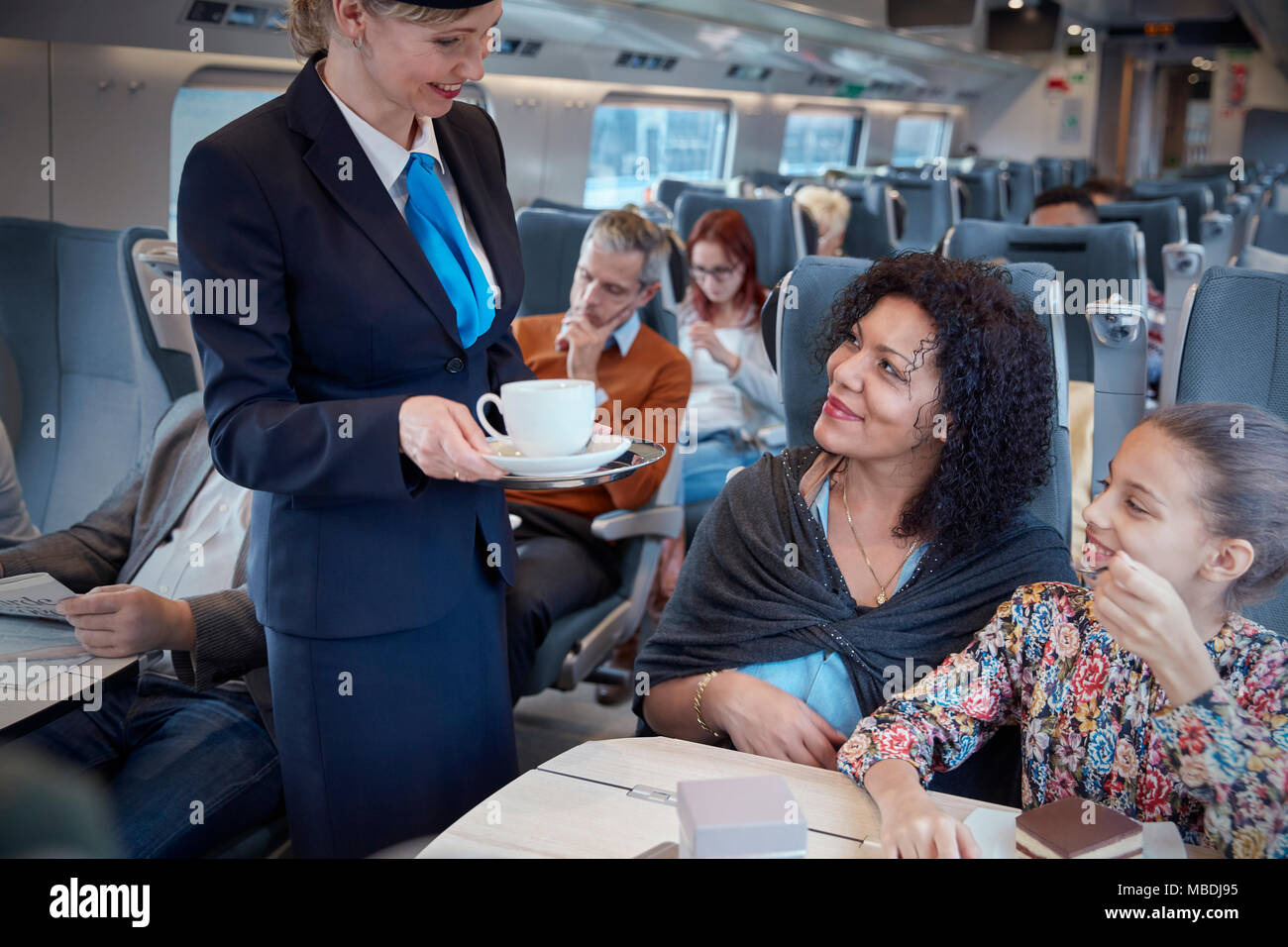 Attendant che serve caffè alla madre con la figlia sul treno passeggeri Foto Stock