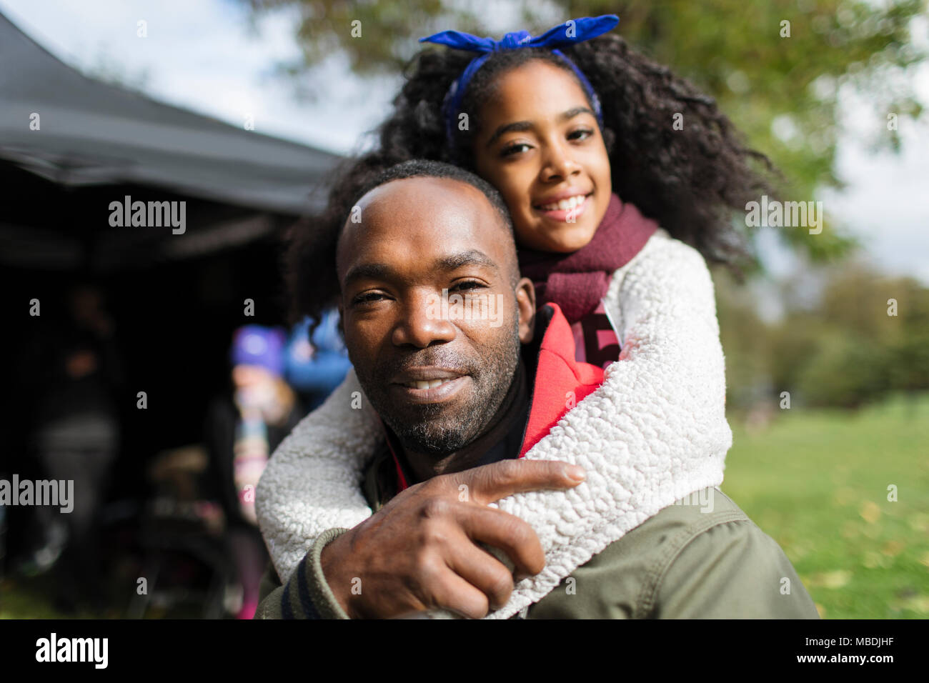 Ritratto di Padre sorridente piggybacking figlia in posizione di parcheggio Foto Stock