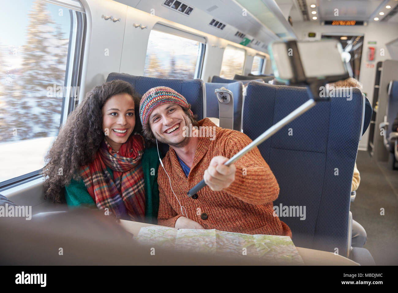 Felice coppia giovane tenendo selfie con selfie stick sul treno passeggeri Foto Stock