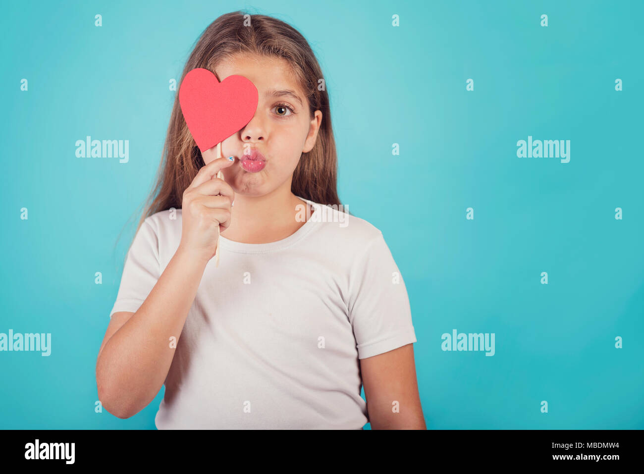 Sorridente ragazza con un cuore che copre il suo occhio Foto Stock