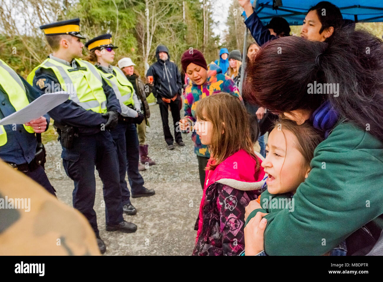 Pipeline anti manifestanti con i bambini piccoli sono leggere un'ingiunzione in quanto il blocco di un camion da ingresso al Kinder Morgan terminale di pipeline, Burnaby B Foto Stock