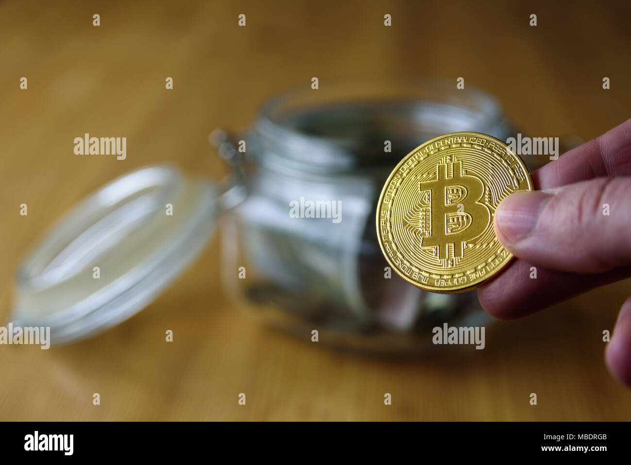 Denaro e jar bitcoin in esso. Mettere mano alle monete in vaso Foto Stock