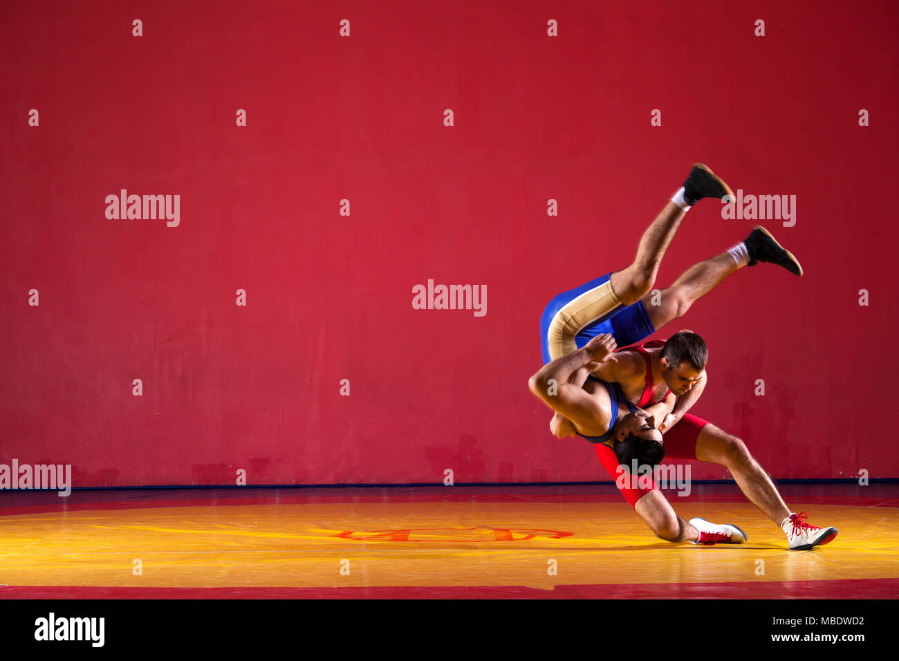 Due greco-romane lottatori in uniforme blu wrestling su un giallo tappeto di wrestling in palestra Foto Stock