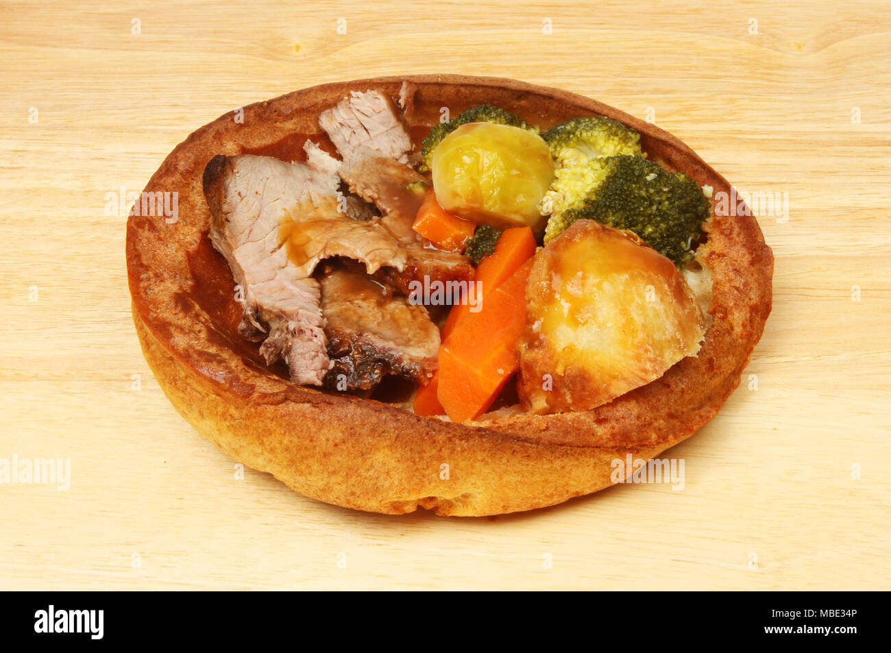 Arrosto di manzo a cena in un gigante di Yorkshire pudding su un tagliere di legno Foto Stock