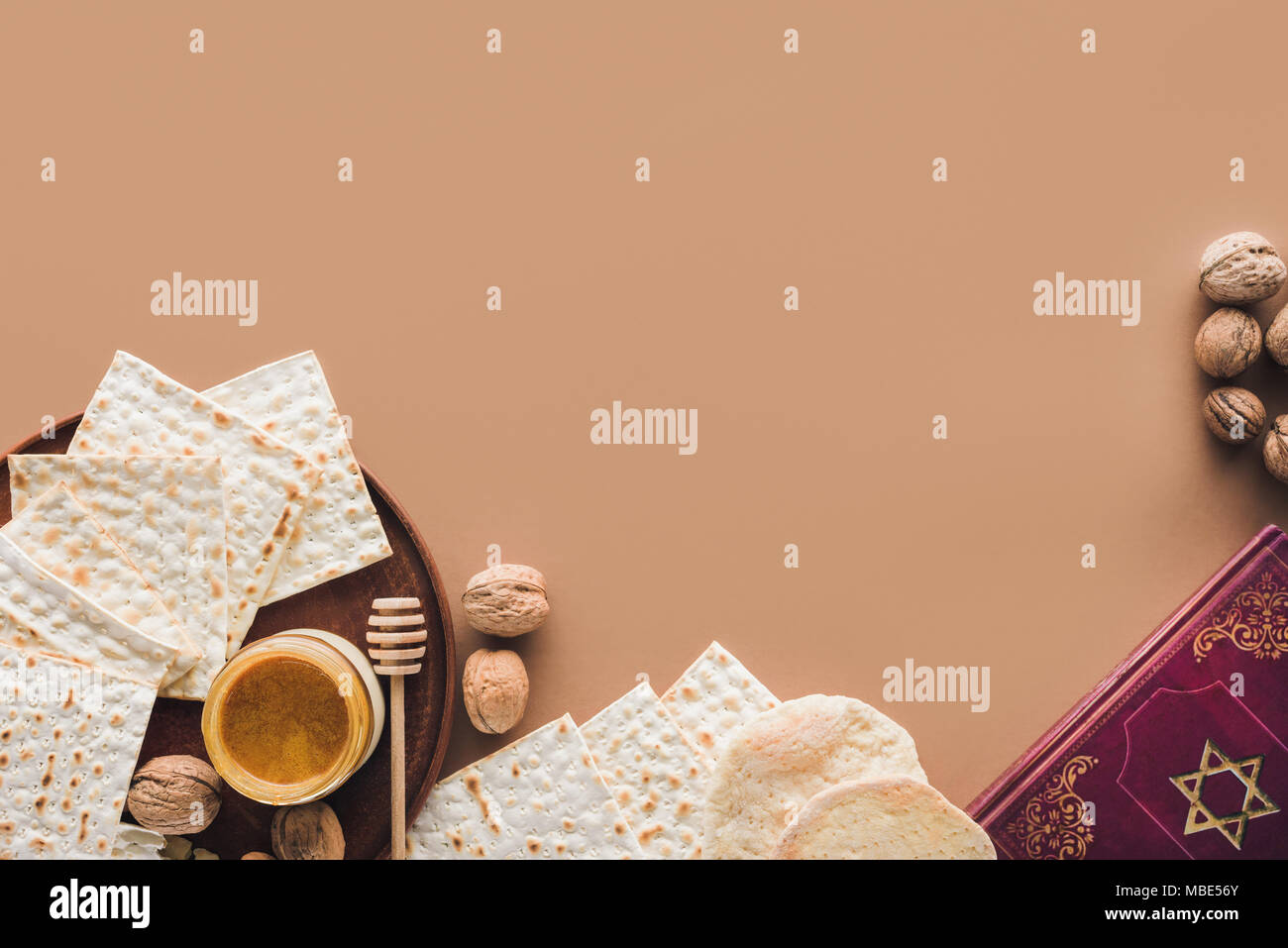 Vista superiore del libro tradizionale con il testo in ebraico e matza con miele sulla superficie marrone Foto Stock