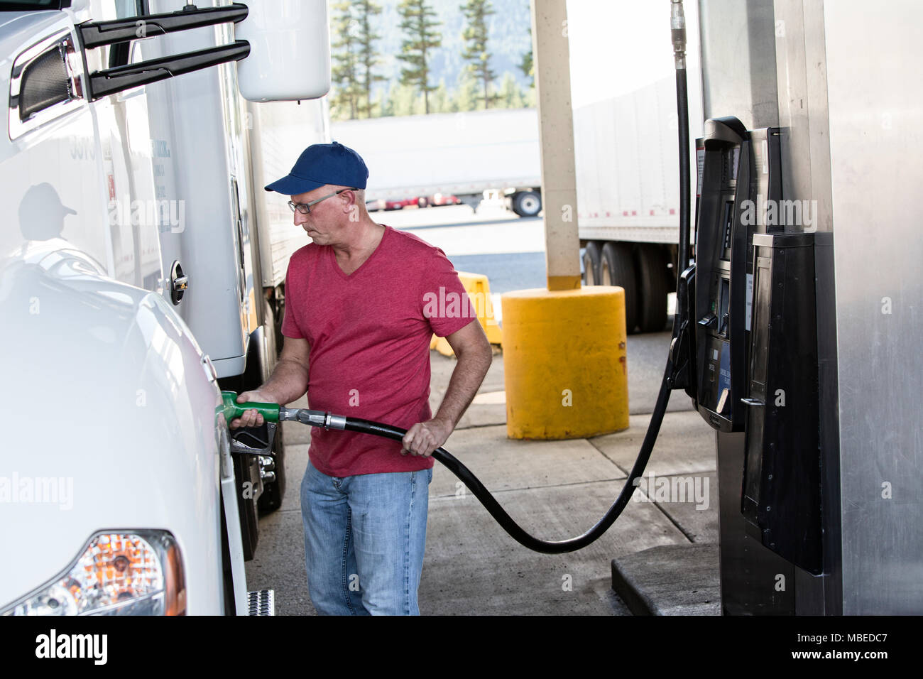 Uomo caucasico camionista mettendo il carburante diesel nel suo carrello a carrello fermo. Foto Stock