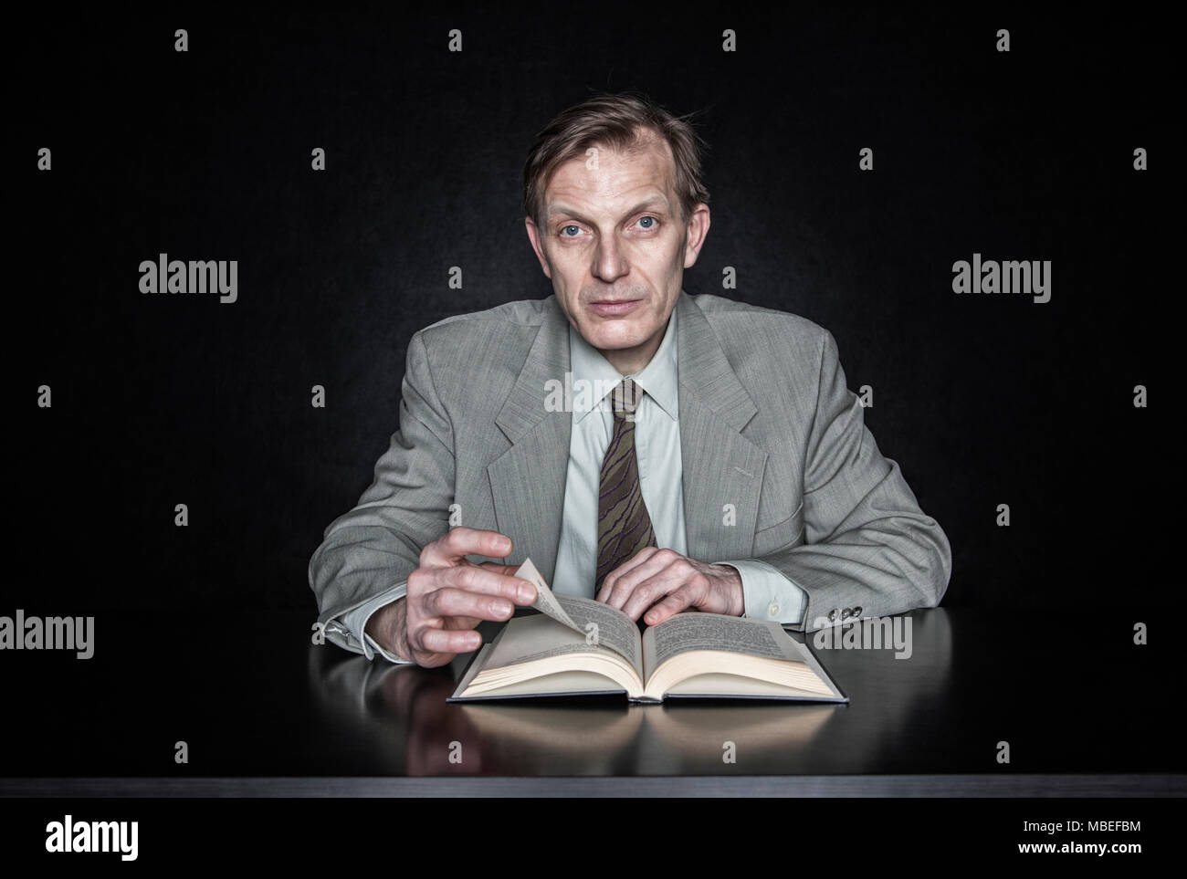 Ritratto in studio di uomo caucasico attore seduto la lettura da un libro aperto. Foto Stock
