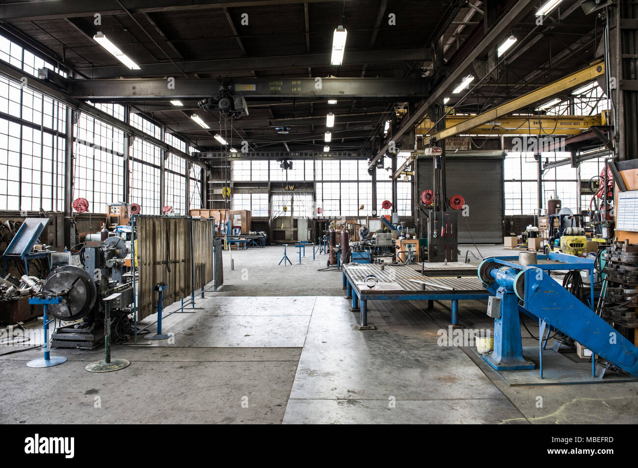 Il pavimento di una fabbrica con macchinari industriali e spazio aperto, presse di metallo e il tettuccio di un ingranaggio di sollevamento e portali. La produzione. Foto Stock