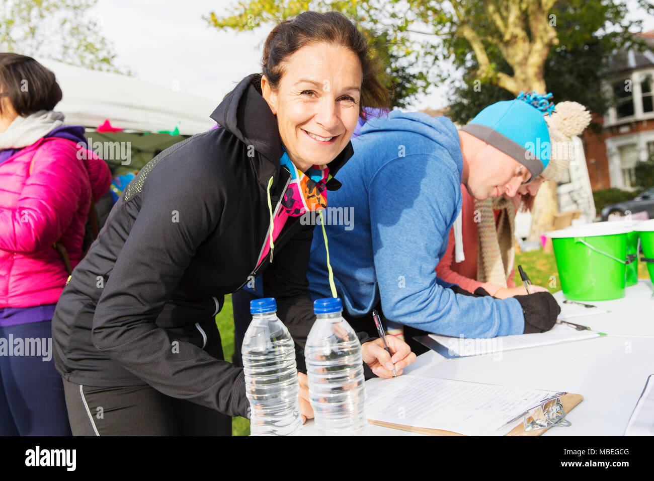 Ritratto di donna sorridente runner il check in presso la carità eseguire in posizione di parcheggio Foto Stock