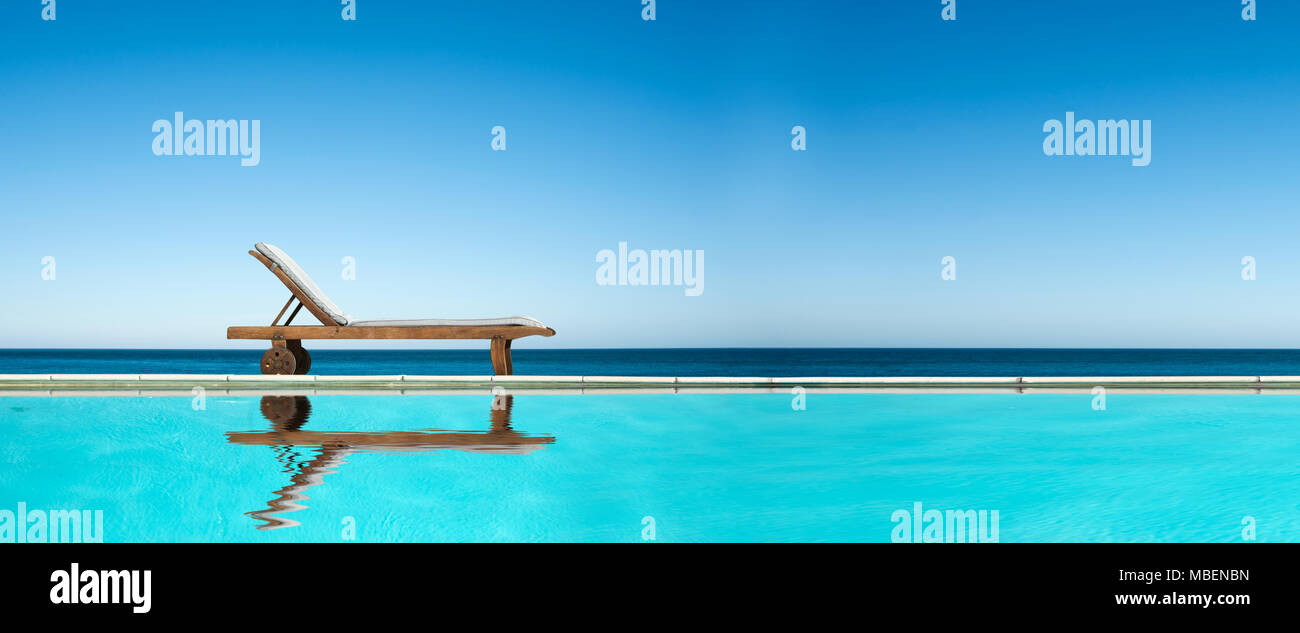 Sedia reclinabile vicino a una piscina, il mare e il cielo azzurro sfondo panoramico Foto Stock