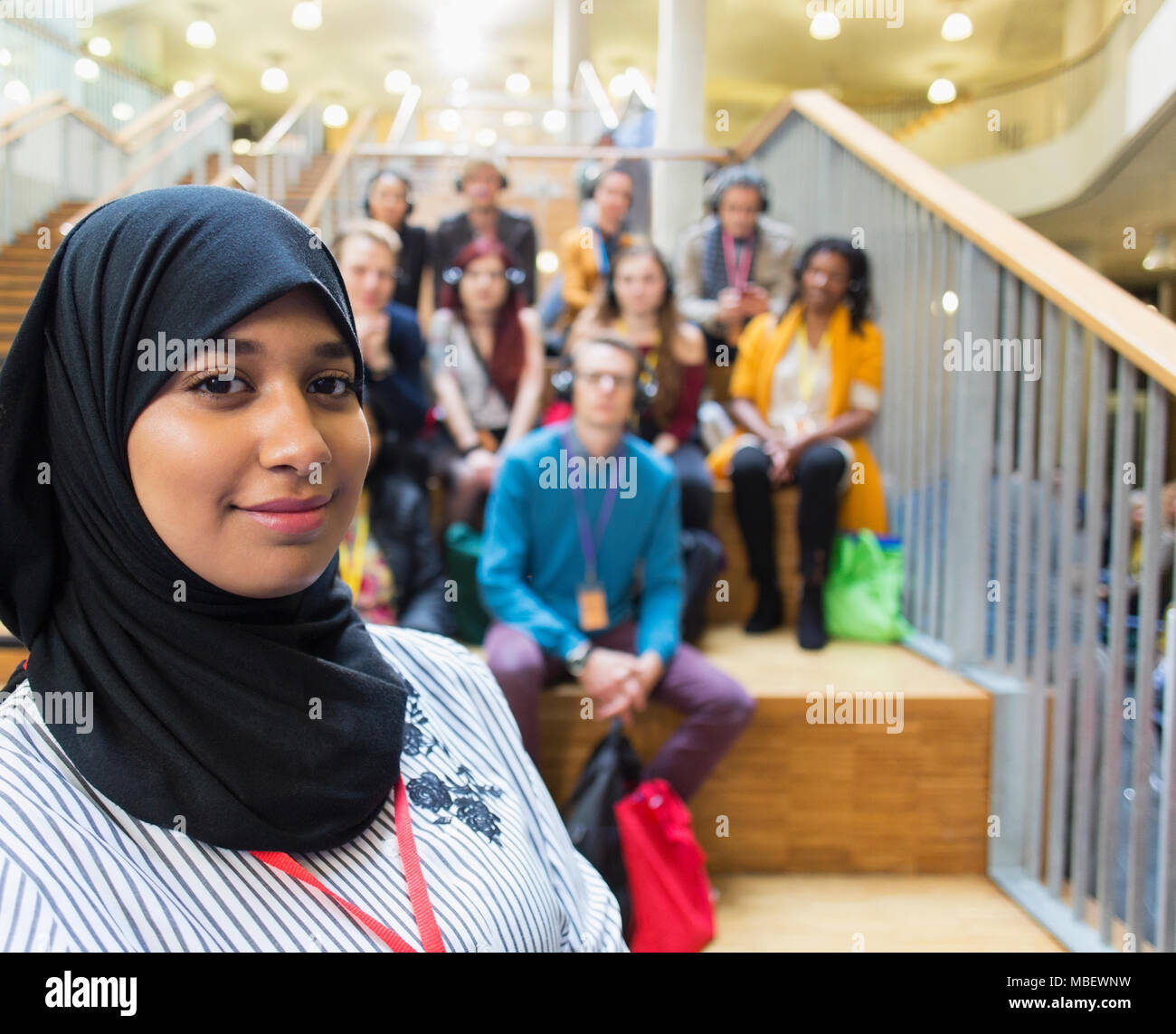 Ritratto femminile fiducioso altoparlante in hijab con il pubblico in background Foto Stock