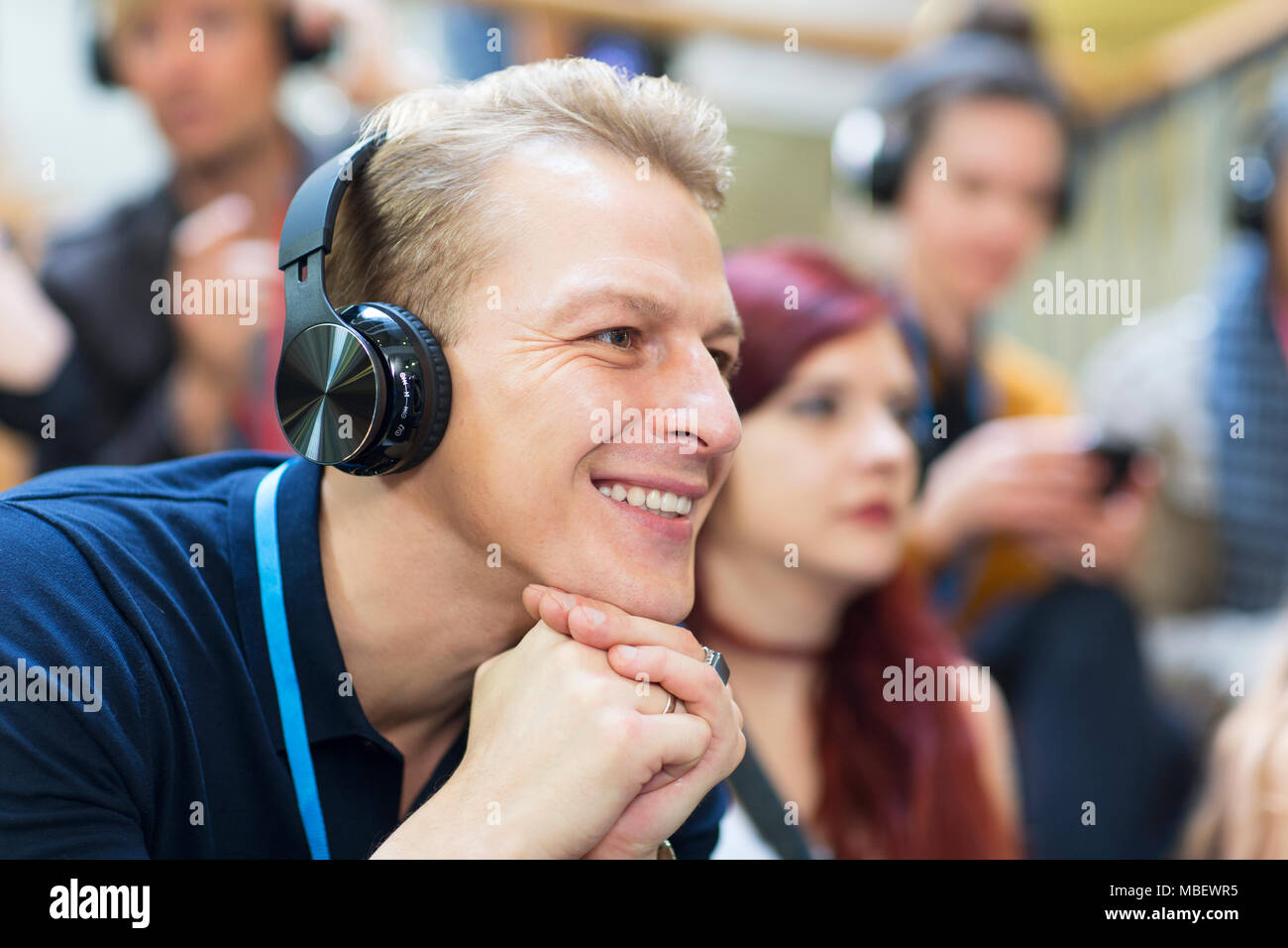 Imprenditore sorridente con ascolto in cuffia in udienza di conferenza Foto Stock