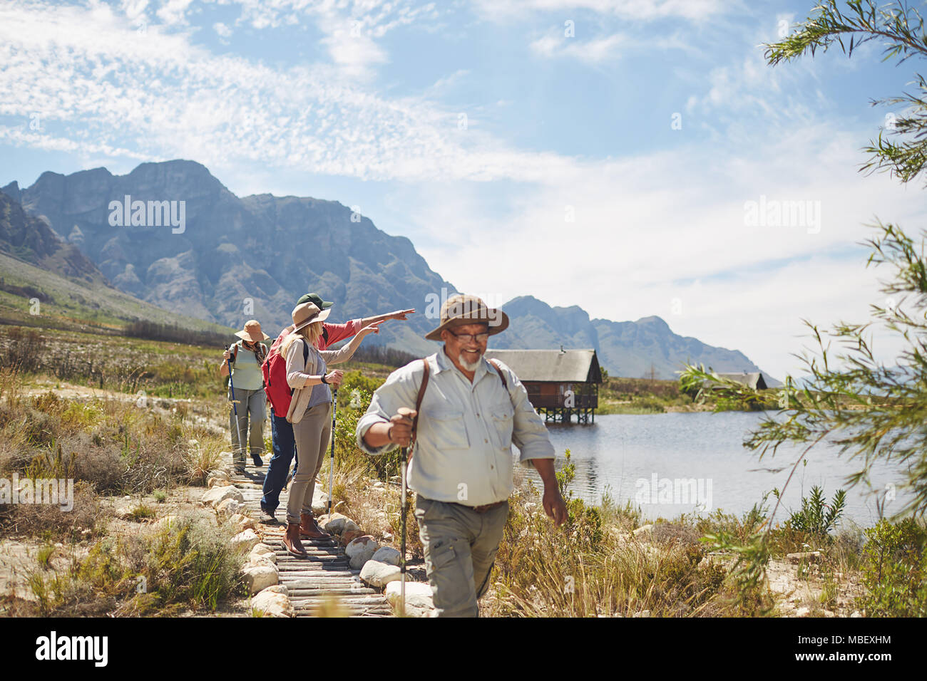 Attiva gli amici senior escursionismo e godendo estiva soleggiata vista lago Foto Stock