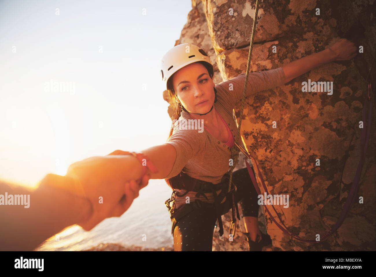 Femmina focalizzato rocciatore raggiungendo per arm Foto Stock