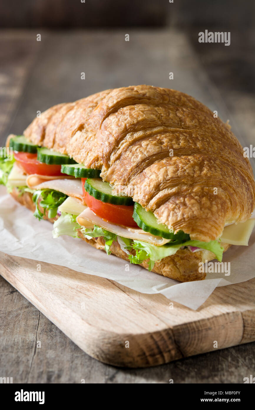 Croissant sandwich con formaggio, prosciutto e le verdure sul tavolo di legno Foto Stock