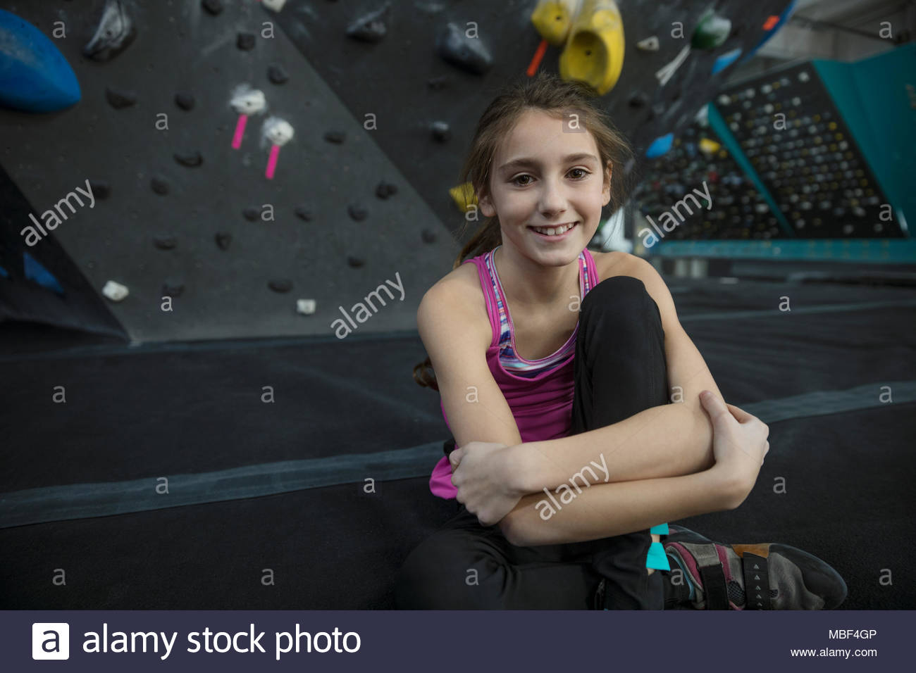 Ritratto sorridente, fiducioso, ragazza forte scalatore a parete di arrampicata in palestra di arrampicata Foto Stock