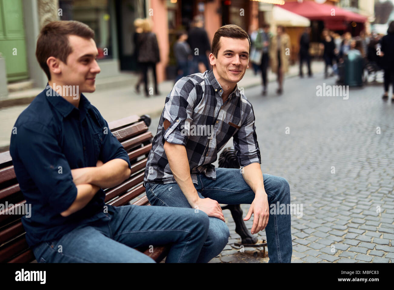 Due uomini di sedersi sulla panchina e talk su strada Foto Stock