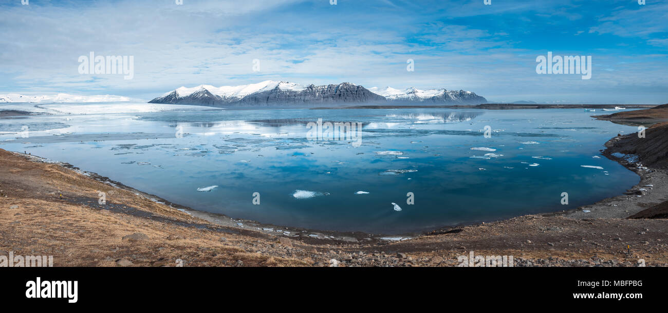 Panorama di Jokulsarlon laguna glaciale a luce diurna e cielo blu con le montagne in Islanda Foto Stock