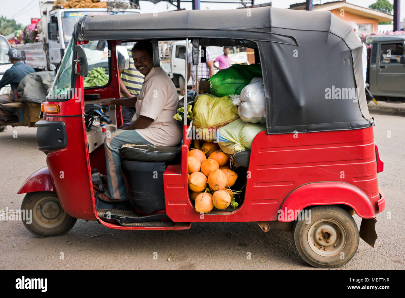 Vista orizzontale di un tuk-tuk driver con una consegna a Dambulla ingrosso di frutta e verdura mercato in Sri Lanka. Foto Stock