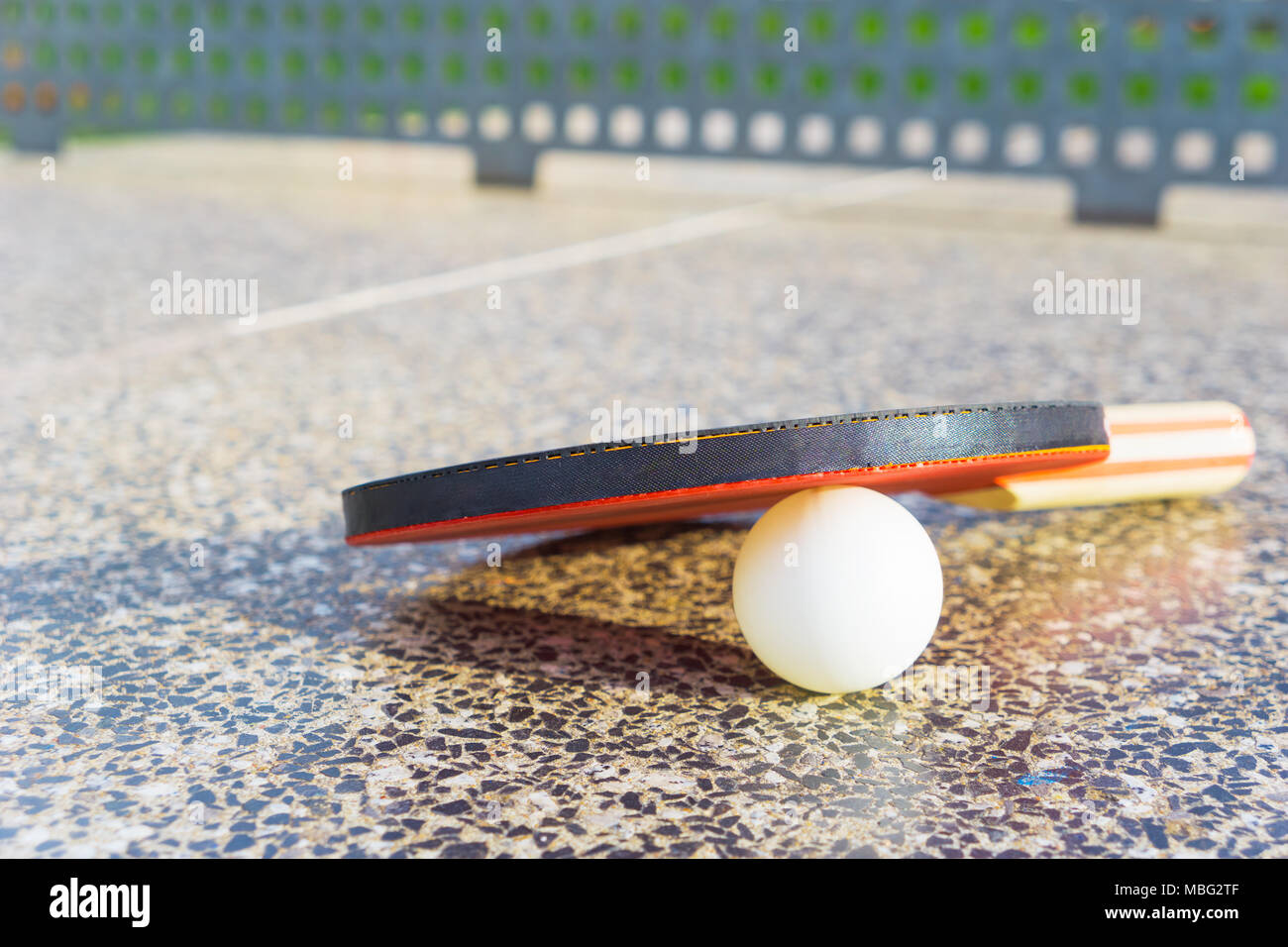 Close-up di un ping-pong pagaia con una tavola di ping-pong sfera bianca su una tavola di ping-pong tavolo in pietra con copia spazio. Sport e tempo libero concept Foto Stock