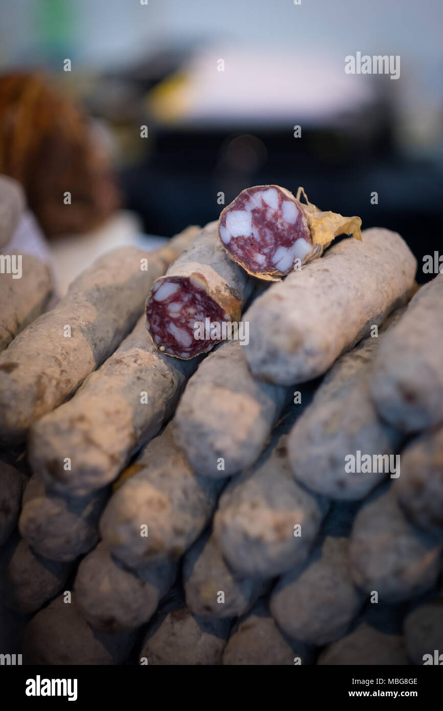 Pila di essiccato salame salsicce, vicino a un mercato con fette di quelli sulla parte superiore Foto Stock