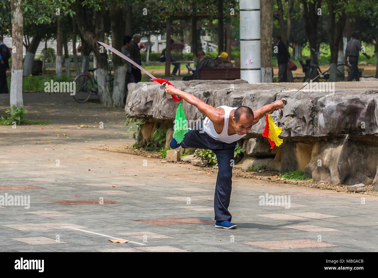 Un uomo cinese sguaina due spade come egli pratica le arti marziali in Yangshuo Park, Yangshuo, Cina. Foto Stock