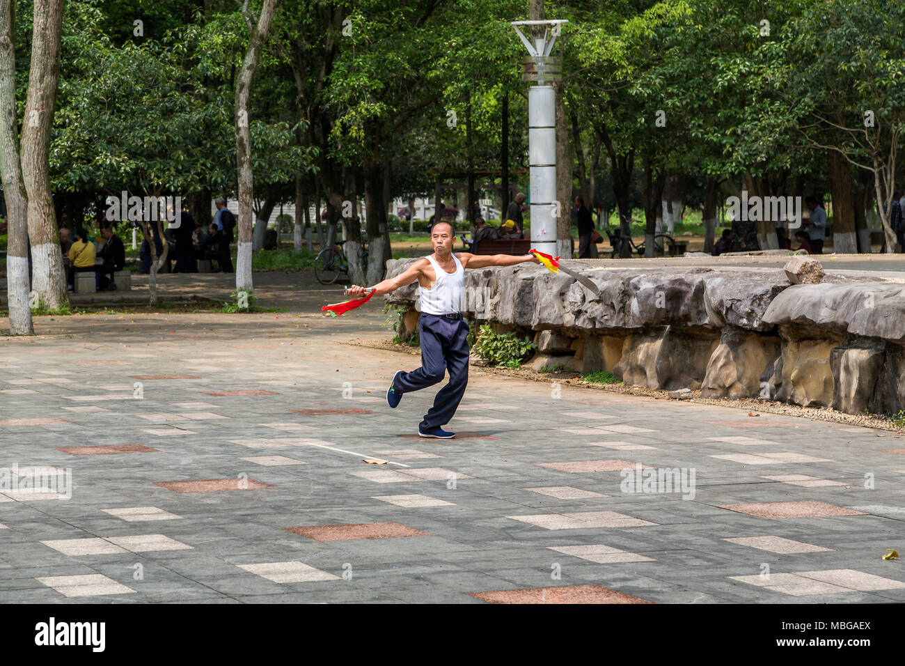 Un uomo cinese sguaina due spade come egli pratica le arti marziali in Yangshuo Park, Yangshuo, Cina. Foto Stock