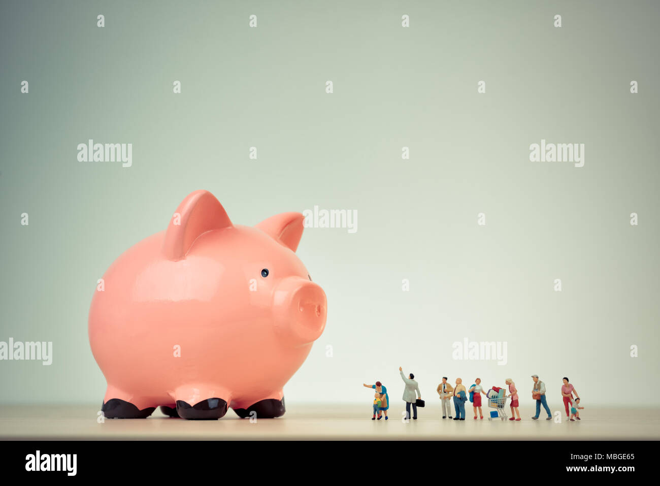 Persone in miniatura e le gigantesche salvadanaio. Famiglia il concetto di bilancio Foto Stock