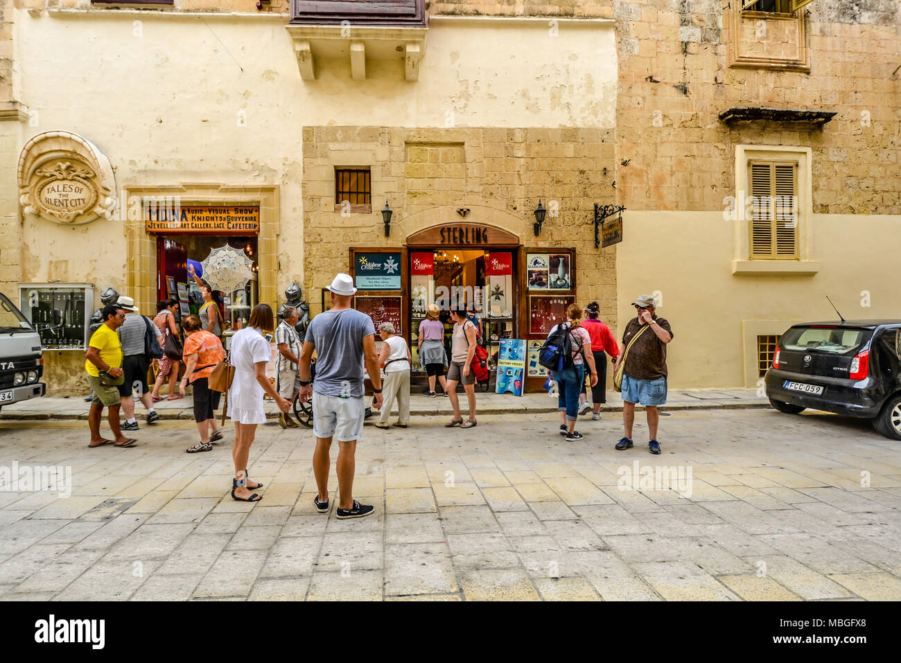 Turisti si riuniscono al di fuori di negozi di souvenir e articoli da regalo nell'antica città di Mdina sull'isola mediterranea di Malta Foto Stock