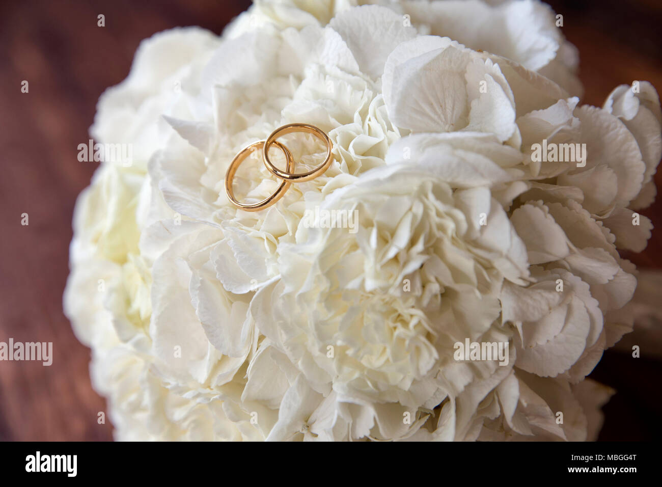 Primo piano orizzontale di nozze anelli d oro su un bianco bouquet di nozze su una tavola di legno Foto Stock