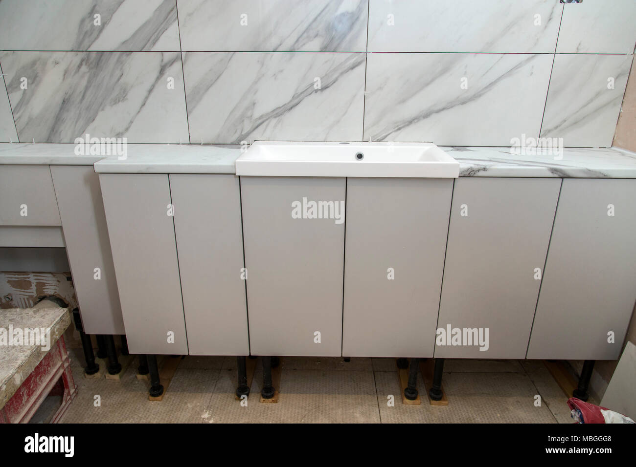 Riattacco di un bagno, armadi, lavello, piano di lavoro e WC unità in posizione, piastrellate di parte ma non intonacando come ancora. Foto Stock
