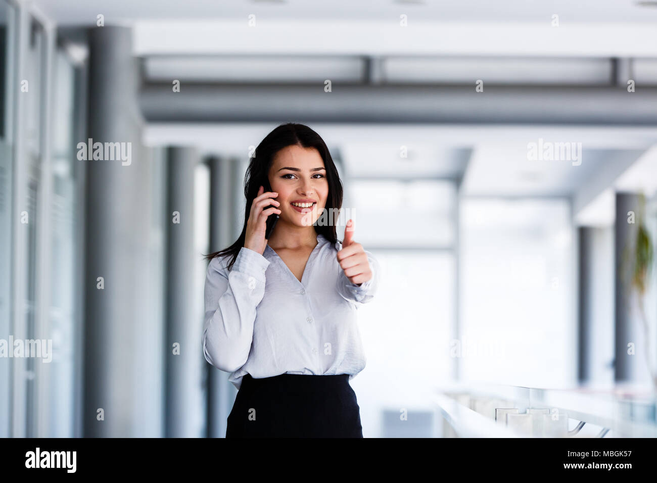 Donna attraente parlando al telefono e mostra thums fino Foto Stock