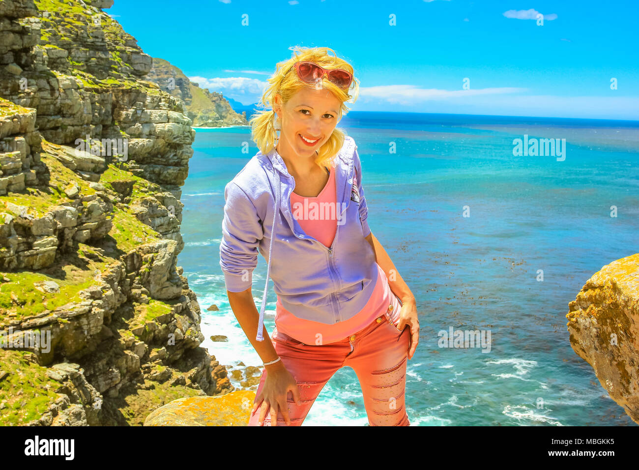 Sud Africa vacanze concetto. Felice donna caucasica a Cape Point promontorio, l'angolo sud-est della Penisola del Capo. Turista femminile godendo al Capo di Buona Speranza parte della Table Mountain NP. Blue sky. Foto Stock