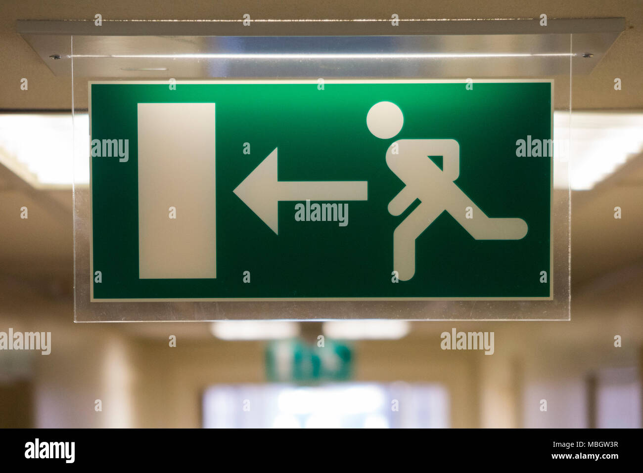 Uscita di emergenza / fire escape il segno di un tipo illuminato, per uso in spazi più scuri. Regno Unito (95) Foto Stock