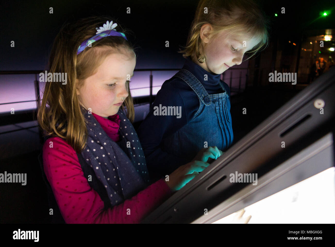 Due giovani sorelle interagenti con interactive nave turistica istruzione pannello informativo all'interno della Mary Rose Museum. Portsmouth Historic Dockyard REGNO UNITO Foto Stock