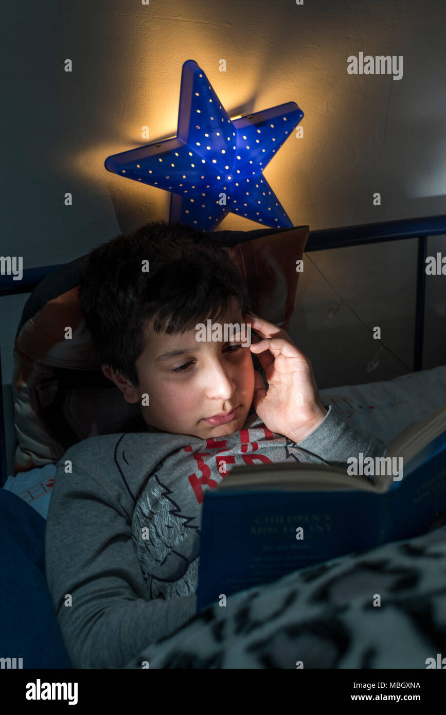 Regno Unito,Surrey, ragazzo legge a letto a tarda notte Foto Stock