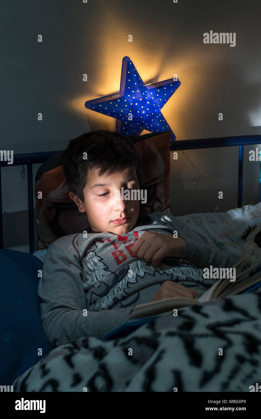 Regno Unito,Surrey.dieci anni ragazzo legge a letto Foto Stock