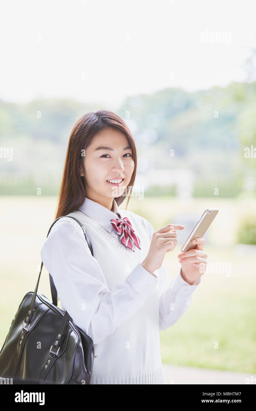 Carino il giapponese studente di scuola superiore in un parco della città Foto Stock