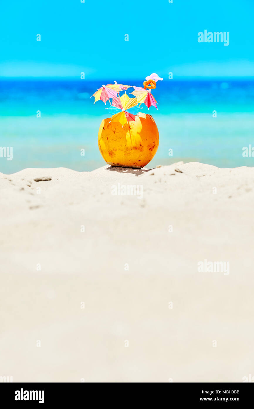 Noce di cocco con ombrelloni colorati e cannucce su una spiaggia, estate vacanza divertente concetto, il fuoco selettivo, spazio per il testo. Foto Stock