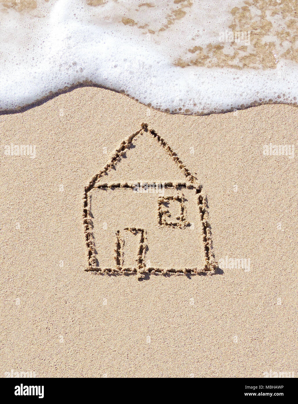 Disegno della casa nella sabbia. Sabbia e mare in scena con il surf e il simbolo della casa. Foto Stock