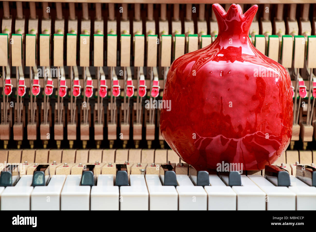 Rosso melograno bibelot sul vicino l immagine di i tasti del pianoforte e interno che mostra le stringhe, martello e la struttura dello sfondo Foto Stock