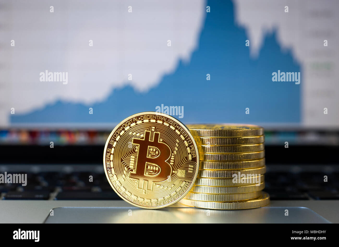 Bitcoins su un computer portatile con la tendenza dei prezzi graffic sullo sfondo Foto Stock