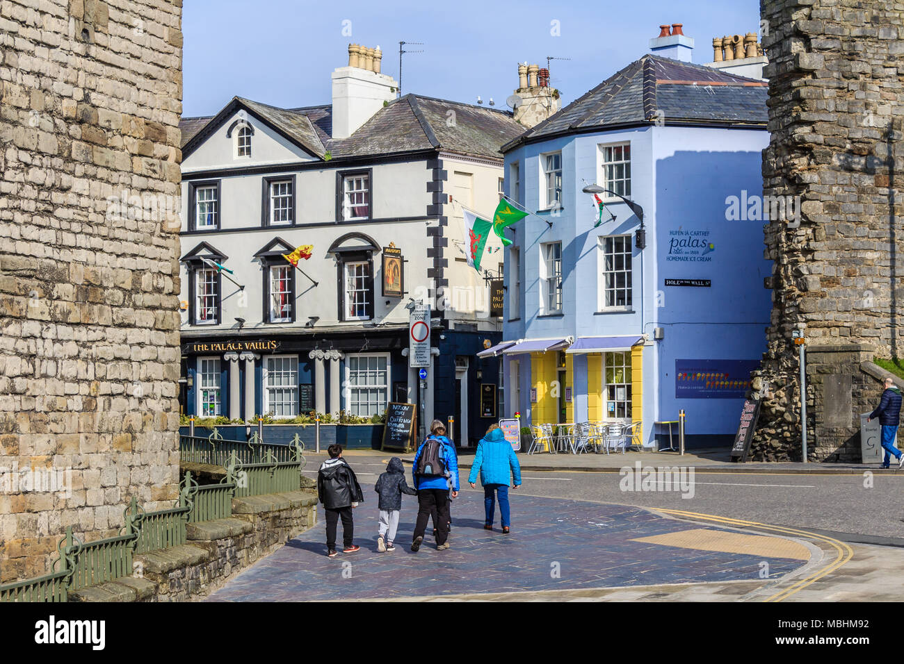 Famiglia di vacanzieri camminare su per la Collina del Castello situato nel centro città a fianco delle mura, Caernarfon, Gwynedd, Wales, Regno Unito. Foto Stock