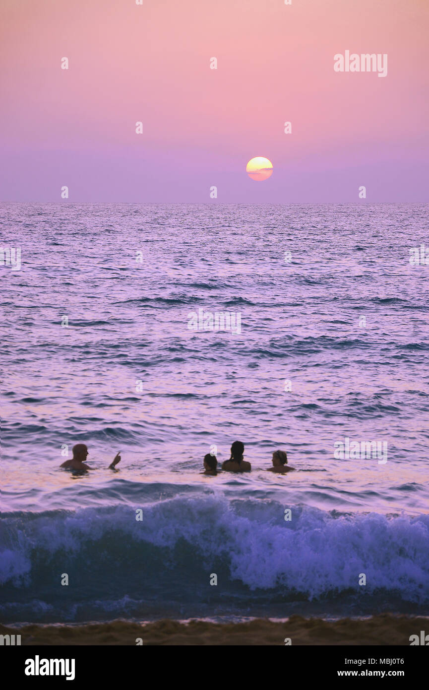 Quattro persone godendo di una serata nuotare al tramonto, Cipro Foto Stock