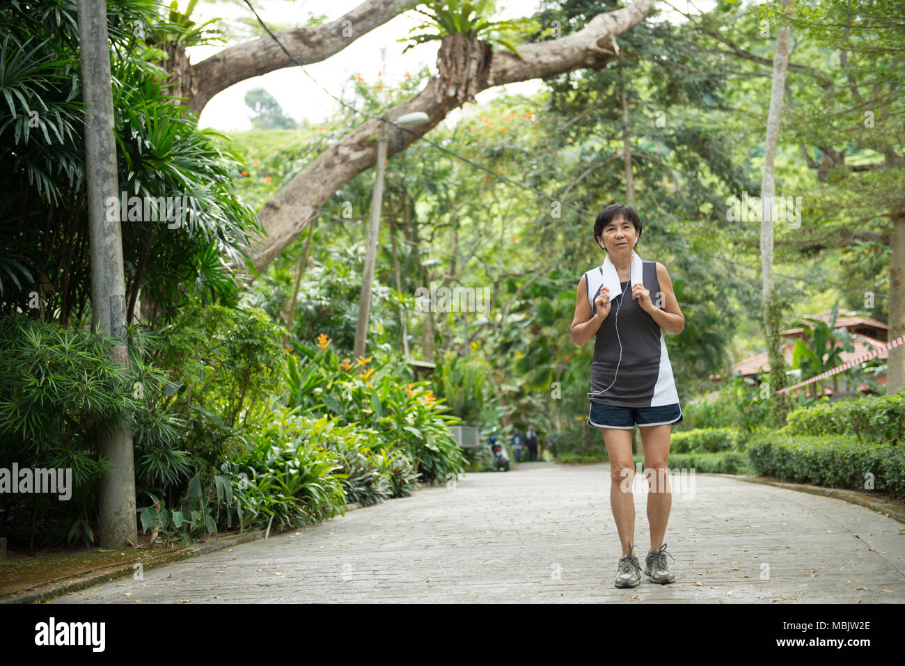 Vista frontale della donna senior jogging attraverso park Foto Stock