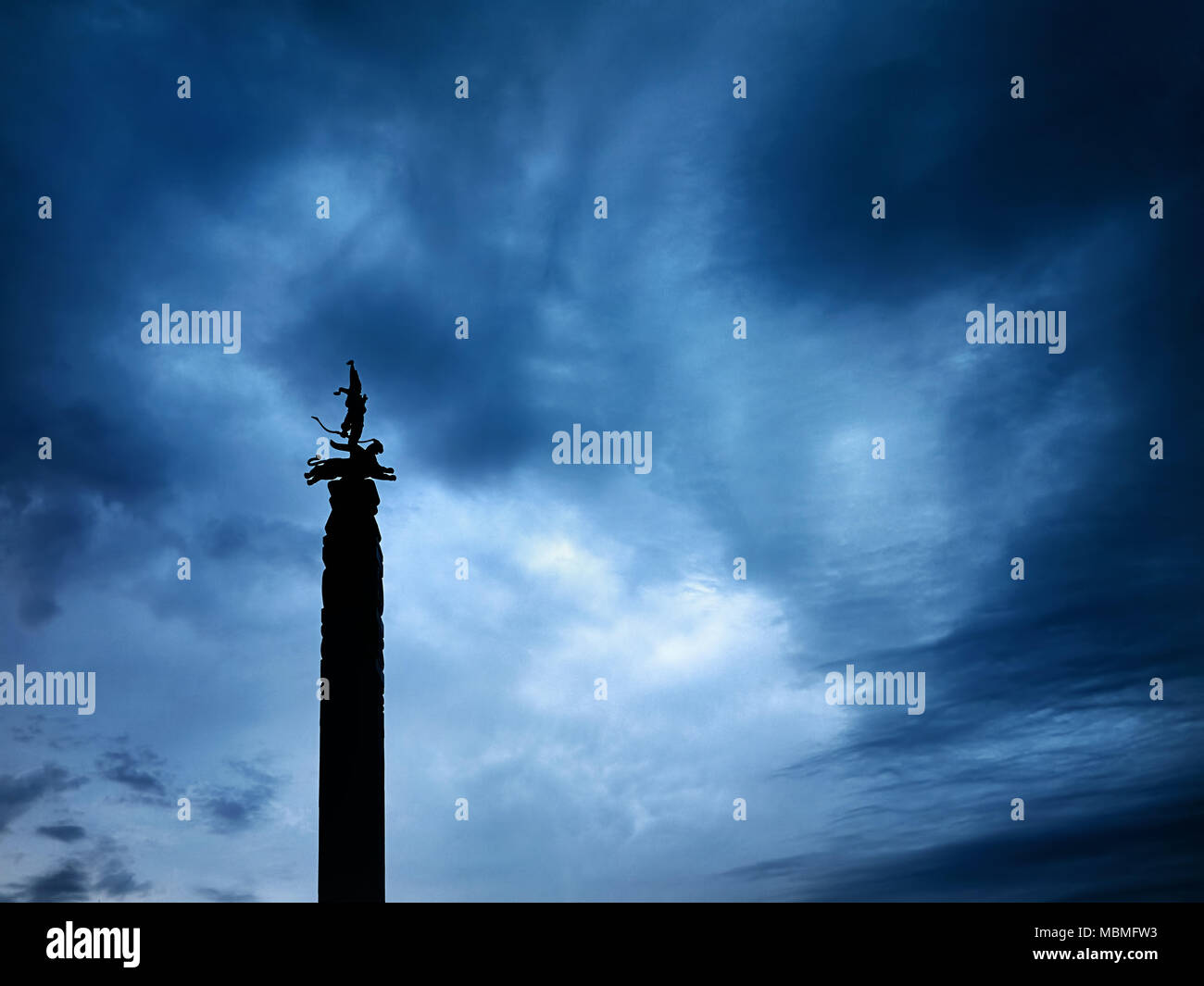 Silhouette della statua con guerriero su Leopard è indipendenza monumento sulla piazza della Repubblica di Almaty in Kazakistan a cielo nuvoloso scuro dello sfondo Foto Stock
