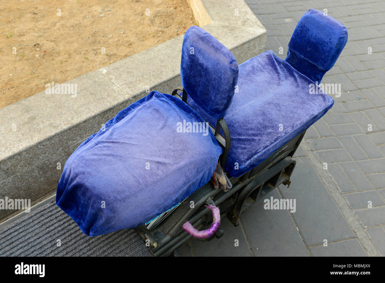 Due sedili rivestiti sulla parte posteriore di un motore elettrico-scooter parcheggiate fuori Yuquan Road stazione della metropolitana sulla linea di Pechino 1, Cina Foto Stock