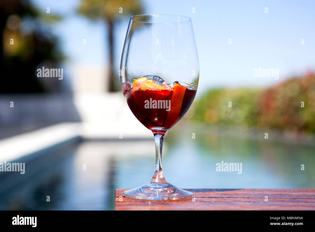 Al di fuori di colpo di un bicchiere di vermouth rosso con cubetti di ghiaccio nei pressi di una piscina Foto Stock