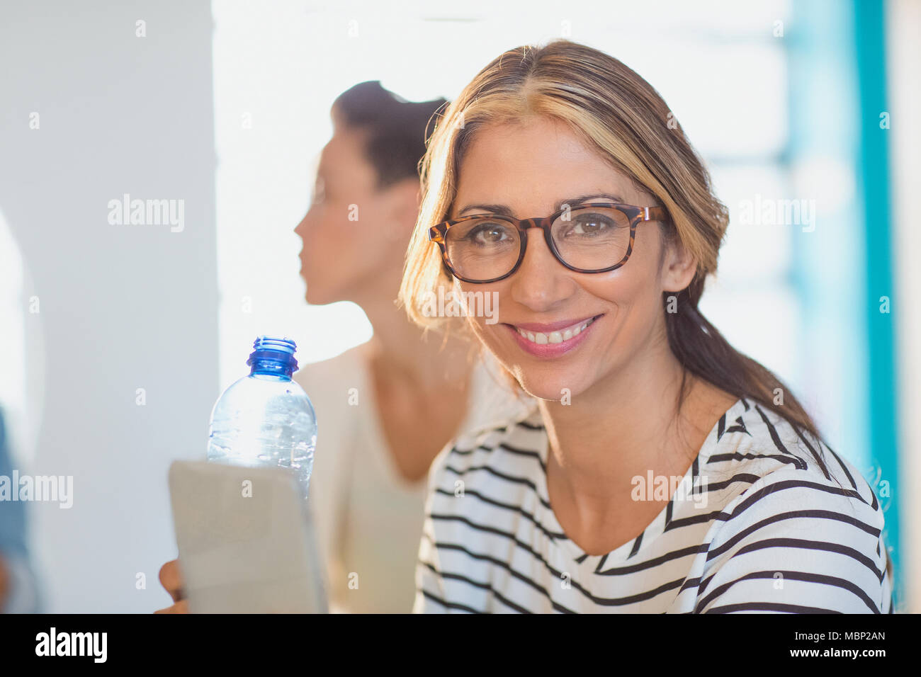 Ritratto sorridente, fiduciosi imprenditrice con tavoletta digitale e una bottiglia d'acqua Foto Stock